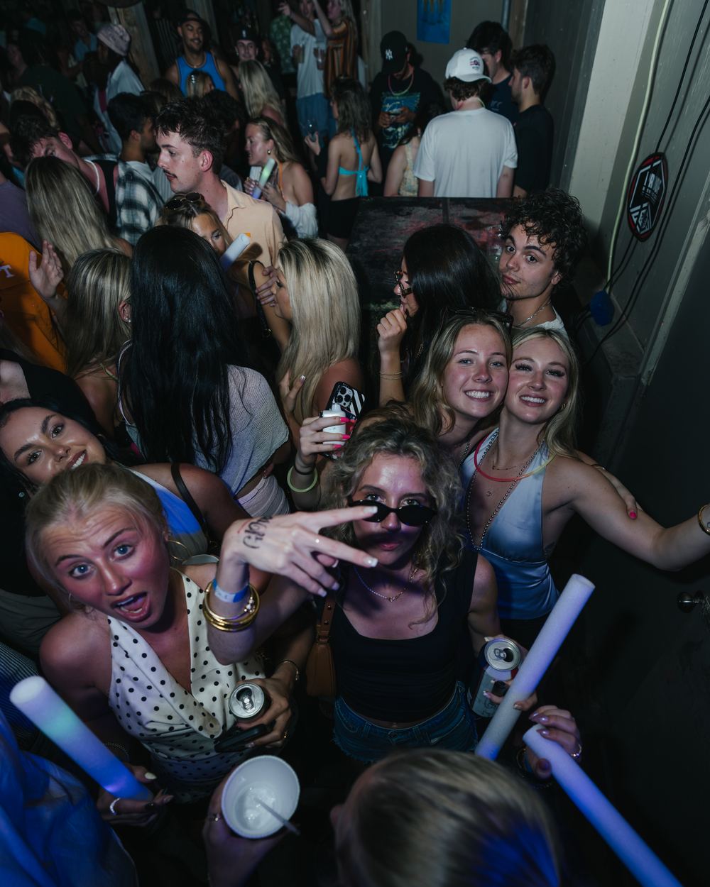 A crew of friends holding glow sticks and posing for the camera at a Panama City Beach spring break party