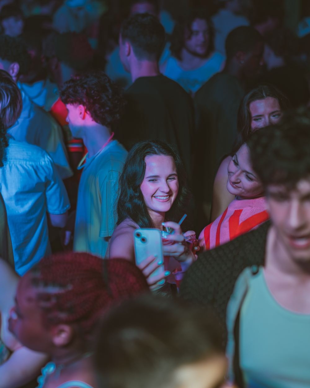 A smiling friend holding up her phone in the crowd at a Panama City Beach spring break party