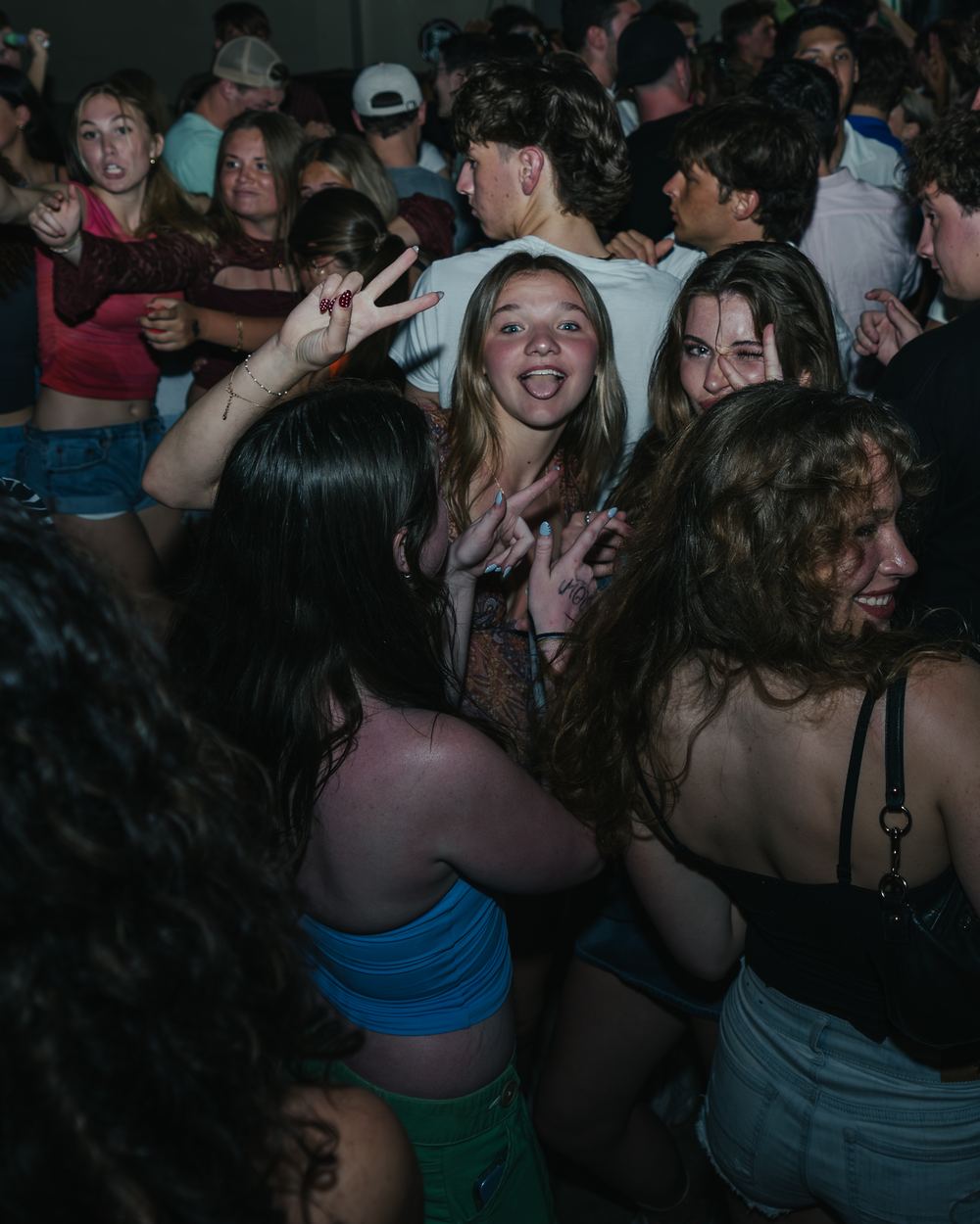 Friends dancing and making peace signs in a packed crowd at a Panama City Beach spring break party